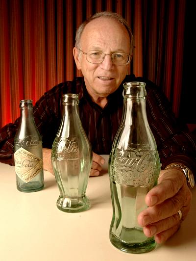 Phil Mooney, director of Archives for The Coca-Cola Company, shows one of the two remaining original contour bottles and displays earlier prototypes